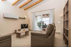 uma sala de estar com duas cadeiras e uma televisão em Villa Alana em Es Mercadal