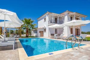 a villa with a swimming pool and two white umbrellas at Villa Orchard in Ambelókipoi