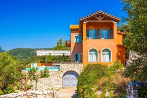 een groot oranje huis bovenop een heuvel bij Villa Agapi in Sivota