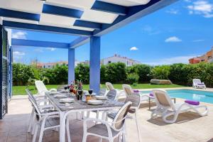 a table and chairs on a patio with a pool at Blue Dream in Cala en Forcat