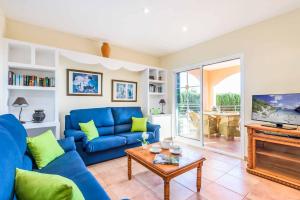 a living room with a blue couch and a tv at Villa Marcolis Mar in Cala Galdana