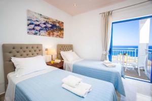 two beds in a bedroom with a view of the ocean at Villa Cyan in Spathíon +15 photos