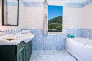 een badkamer met een wastafel, een bad en een raam bij Villa Agapi in Sivota +28 foto's