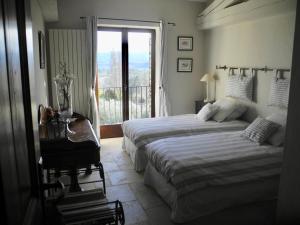 een slaapkamer met 2 bedden, een tafel en een raam bij OUSTAU DE PIERA in Gordes