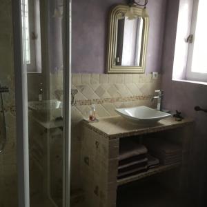 uma casa de banho com um lavatório e uma cabina de duche em vidro. em OUSTAU DE PIERA em Gordes