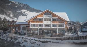 a large building with snow on top of it at Ahrner Wirt Apartments in San Giovanni in Val Aurina