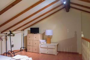 Cette chambre mansardée comprend un lit et une télévision sur une commode. dans l'établissement Kanakades, à Kanakádes