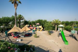 a playground with a slide and play equipment and palm trees at African Beach Hotel-Residence in Manfredonia