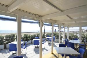a patio with tables and chairs and the beach at African Beach Hotel-Residence in Manfredonia