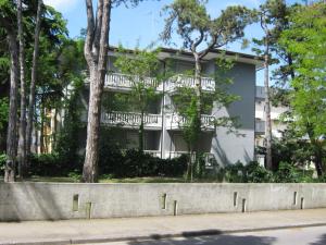 un edificio blanco con árboles delante de él en Condominio Rio Chico, en Lignano Sabbiadoro
