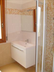 y baño con lavabo blanco y ducha. en Condominio Rio Chico, en Lignano Sabbiadoro