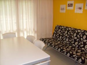 un sofá en una habitación con mesa y sillas en Condominio Rio Chico, en Lignano Sabbiadoro