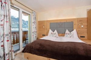 a bedroom with a large bed and a large window at Seehotel St Hubertus in Pertisau