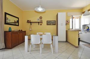 トッレ・サン・ジョヴァンニ・ウジェントにあるDea Minerva Apartment by Salento Affittiのキッチン(ダイニングテーブル、白い椅子付)