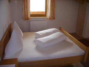 ein Bett mit zwei weißen Kissen und einem Fenster in der Unterkunft Haus Birkenheim in Sölden