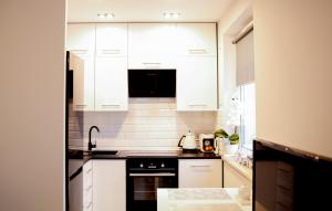 a kitchen with white cabinets and a stove top oven at Apartament Prezydent in Gorzów Wielkopolski