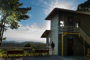 a man standing in front of a building with a porch at Hotel Flor de Bromelia in Monteverde Costa Rica