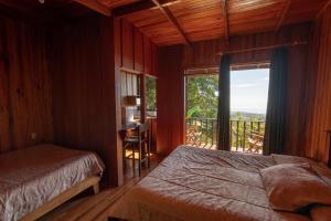 a bedroom with a bed and a window with a balcony at Hotel Flor de Bromelia in Monteverde Costa Rica