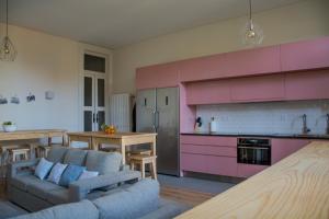 a living room with a couch and a kitchen with pink cabinets at Sweet Swell in Porto