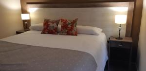 1 dormitorio con 1 cama blanca y 2 lámparas en COMPLEJO LOS GUINDOS - USHUAIA FLAT en Ushuaia