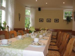 un comedor con una mesa larga con platos y tazas en Pension Kastanienhof en Zeulenroda