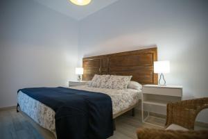 Schlafzimmer mit einem Bett mit einem Kopfteil aus Holz in der Unterkunft Apartamentos Catedral in Málaga