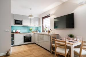 a kitchen with white cabinets and a table with chairs at Marinus Apartments SPA - with pool and sauna in Gdańsk