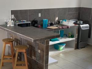 a kitchen with a counter with a stove and stools at New House in Puerto Morelos, Riviera Maya in Puerto Morelos