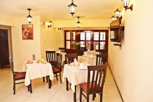 a dining room with tables and chairs and a television at Apart Hotel Caminos del Inca in Lima
