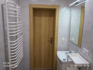 Łazienka z drewnianymi drzwiami i umywalką w obiekcie Apartament Sofia Agroturystyka w mieście Ryczów