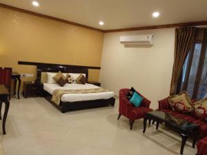 a hotel room with a bed and two chairs at Pink Pearl Hotel in Jaipur