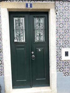 une porte verte sur un bâtiment avec un panneau. dans l'établissement Amazing flat in Madragoa, à Lisbonne