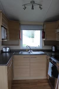 a kitchen with a sink and a window at 2 Bed Static Caravan @ Hoburne Devon Bay in Paignton
