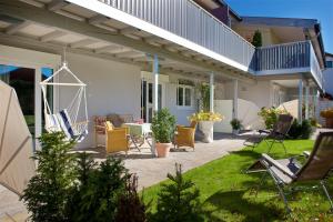 a patio with chairs and a table in a yard at Landhotel Herzberger garni Zimmer & Ferienwohnungen in Scheidegg