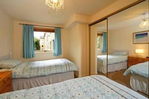 a bedroom with two beds and a mirror at 3 Albany Apartments - Oban in Oban