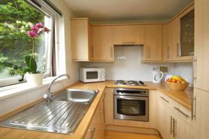 a kitchen with wooden cabinets and a sink and a window at 3 Albany Apartments - Oban in Oban