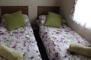 two twin beds in a bedroom with green pillows at 3 Bed Static Caravan @ Hoburne Devon Bay in Paignton