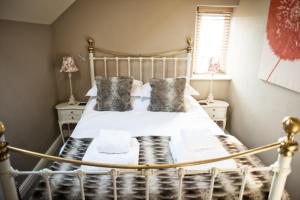 a bedroom with a white bed with pillows and a window at Shippon Cottage - Brosterfield Farm in Eyam