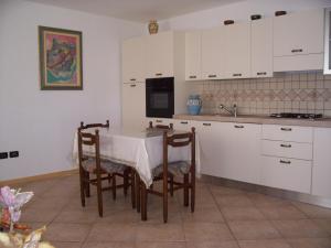 una cocina con mesa y algunos armarios blancos en Casa Iride, en Canal San Bovo