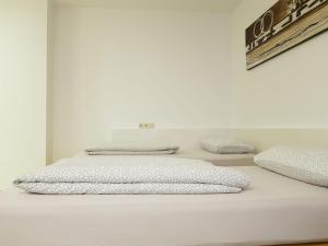 Una cama blanca con tres almohadas encima. en Apartment Metzingen City, en Metzingen