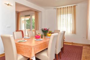 a dining room with a wooden table and white chairs at Villa Fontana 2 in Suko&scaron;an