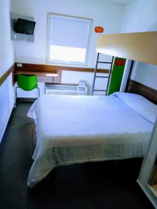 a bedroom with a white bed and a television at Hotel Hi ! Torreon Aeropuerto-Galerías in Torreón