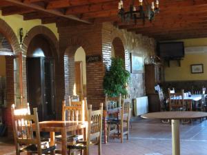 una sala da pranzo con tavoli, sedie e TV di Hostal Rest. Campoabierto a Valencia de las Torres