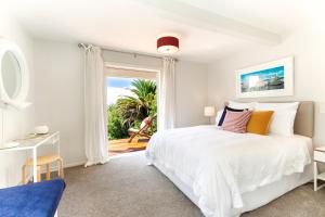 a white bedroom with a bed and a window at Eight on Church - near Mudbrick & Cable Bay in Oneroa