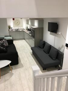 a living room with a black couch and a kitchen at The Snap Pad Boutique Apartment in Royal Tunbridge Wells