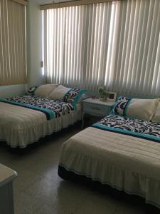 Cette chambre comprend deux lits et une fenêtre avec des rideaux. dans l'établissement Aca life, à Acapulco