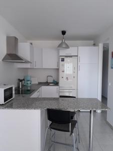 a kitchen with a counter and a white refrigerator at Tu rincon en Playa de Melenara in Telde +16 photos
