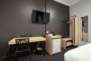 a hotel room with a bed, desk and television at Nightcap at the Charles Hotel in Wollongong