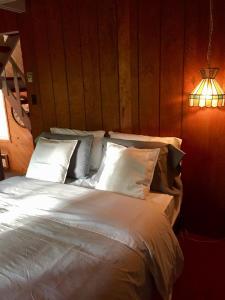 sypialnia z dużym łóżkiem z białą pościelą i poduszkami w obiekcie Le Rustique Orford Domaine Cheribourg w mieście Magog-Orford