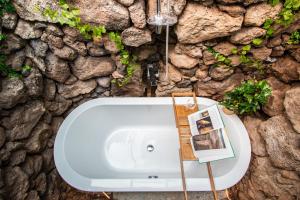 a white bath tub in front of a stone wall at "NEW" Deluxe designer Villa Infinity, with Panoramic sea views,own exclusive heated private pool, subtropical gardens in Tías +19 photos